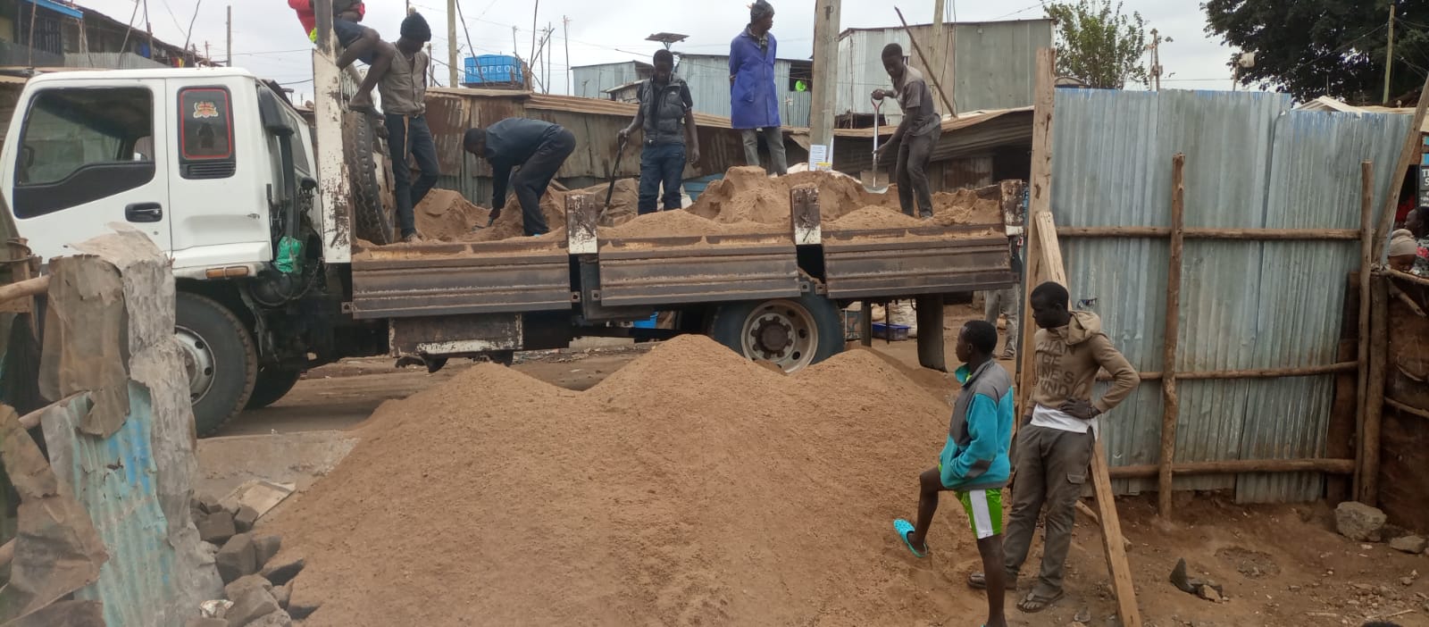 A picture of men shovelling sand off a truck